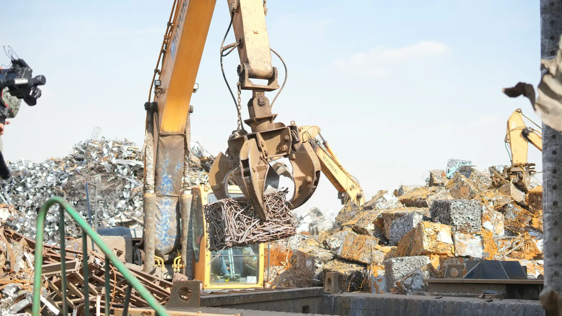Máy xúc gắp phế liệu kim loại tại bãi tập kết